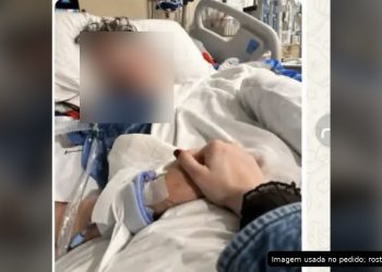 Pessoa em leito hospitalar, com o rosto ocultado por privacidade