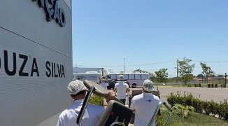 Profissionais de saúde transportando equipamentos em área externa de uma unidade médica.
